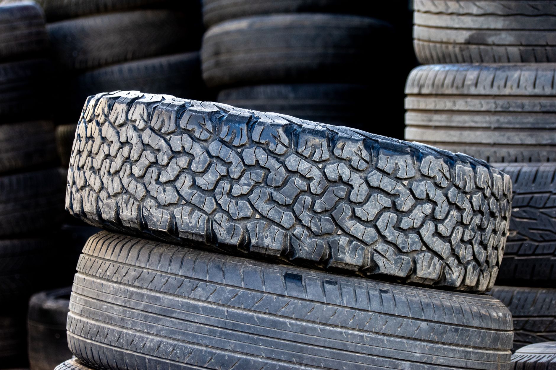 Stacked automotive tires with rugged tread patterns in an outdoor setting