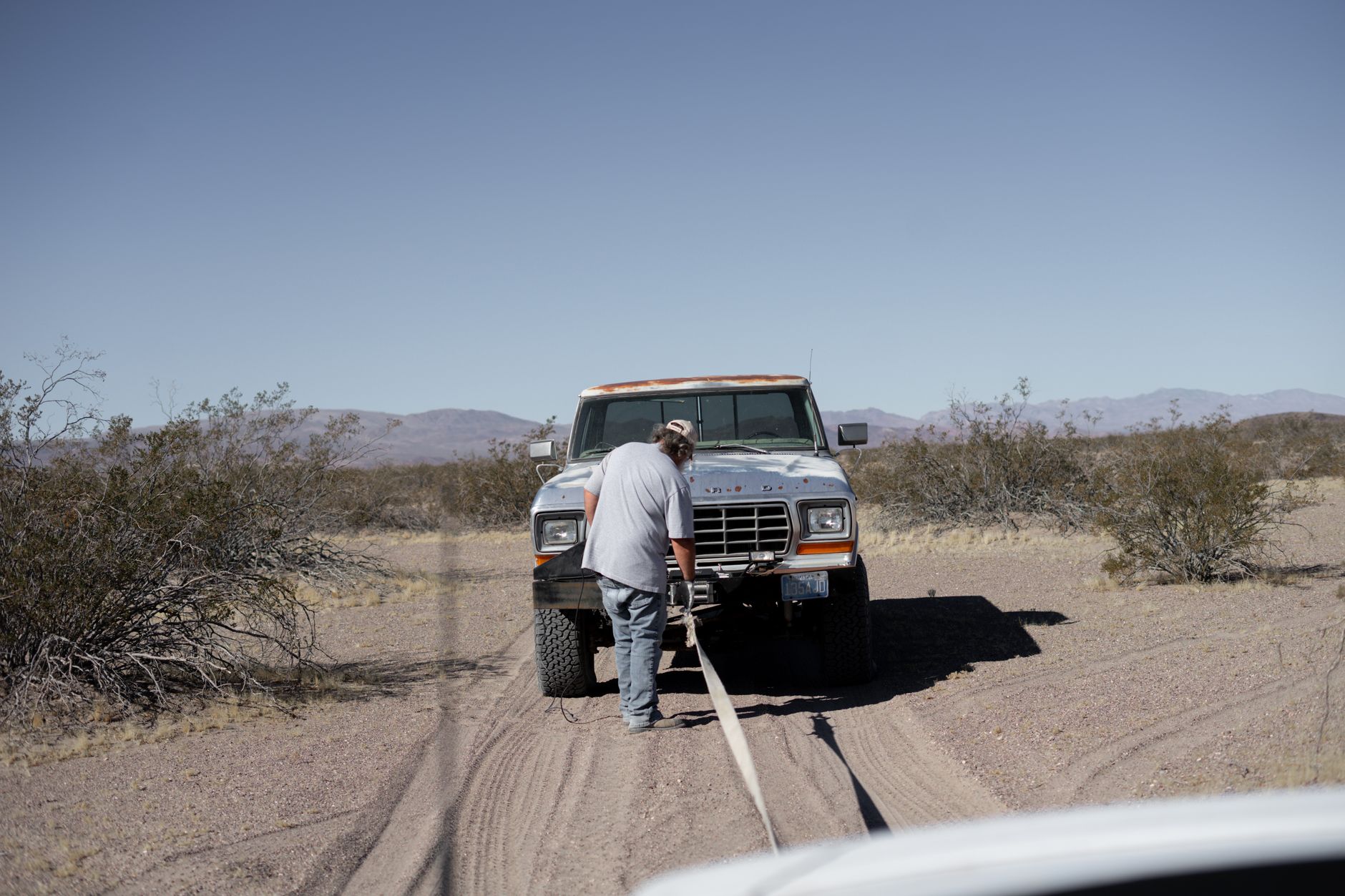 A man assisting a stranded pickup truck on a rural road