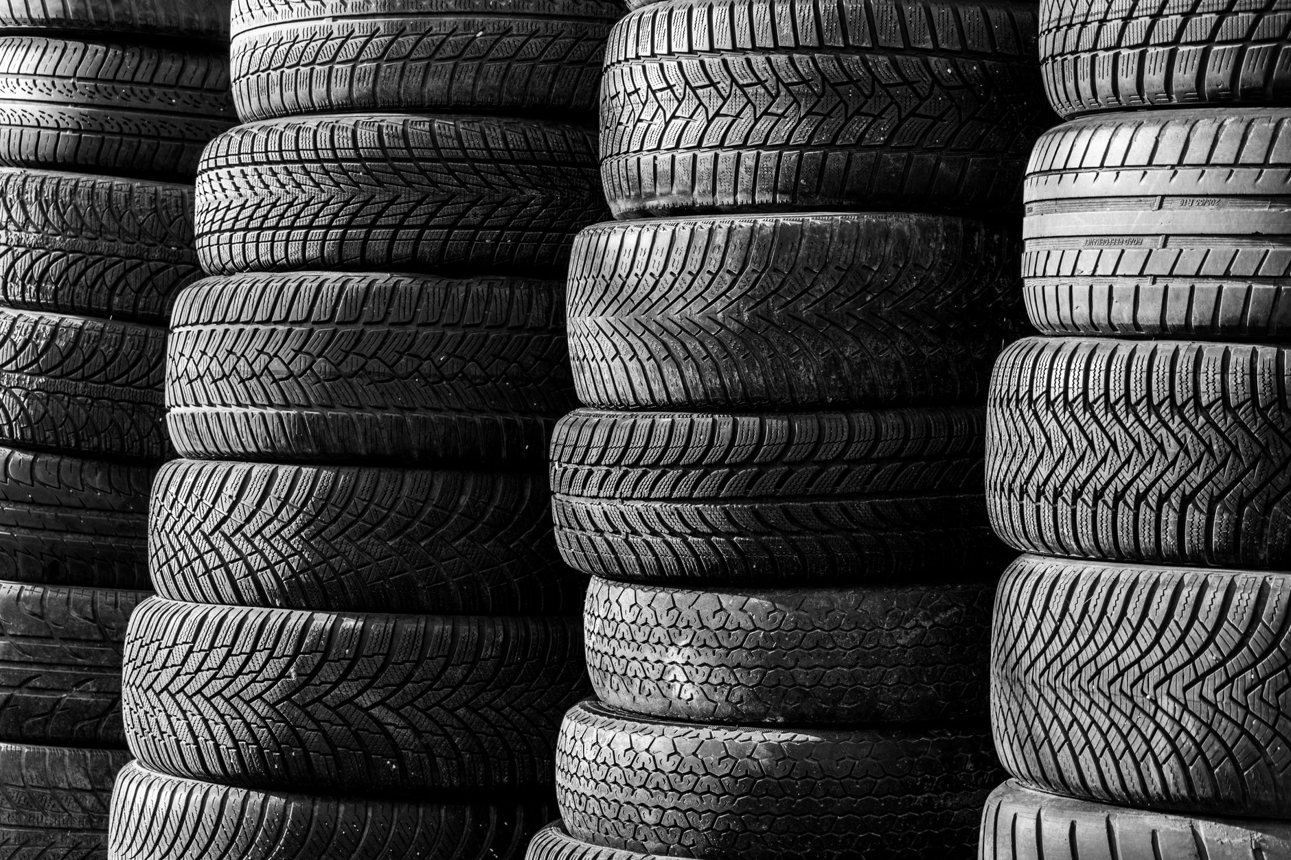 Black and white image of stacked vehicle tires showing different tread patterns