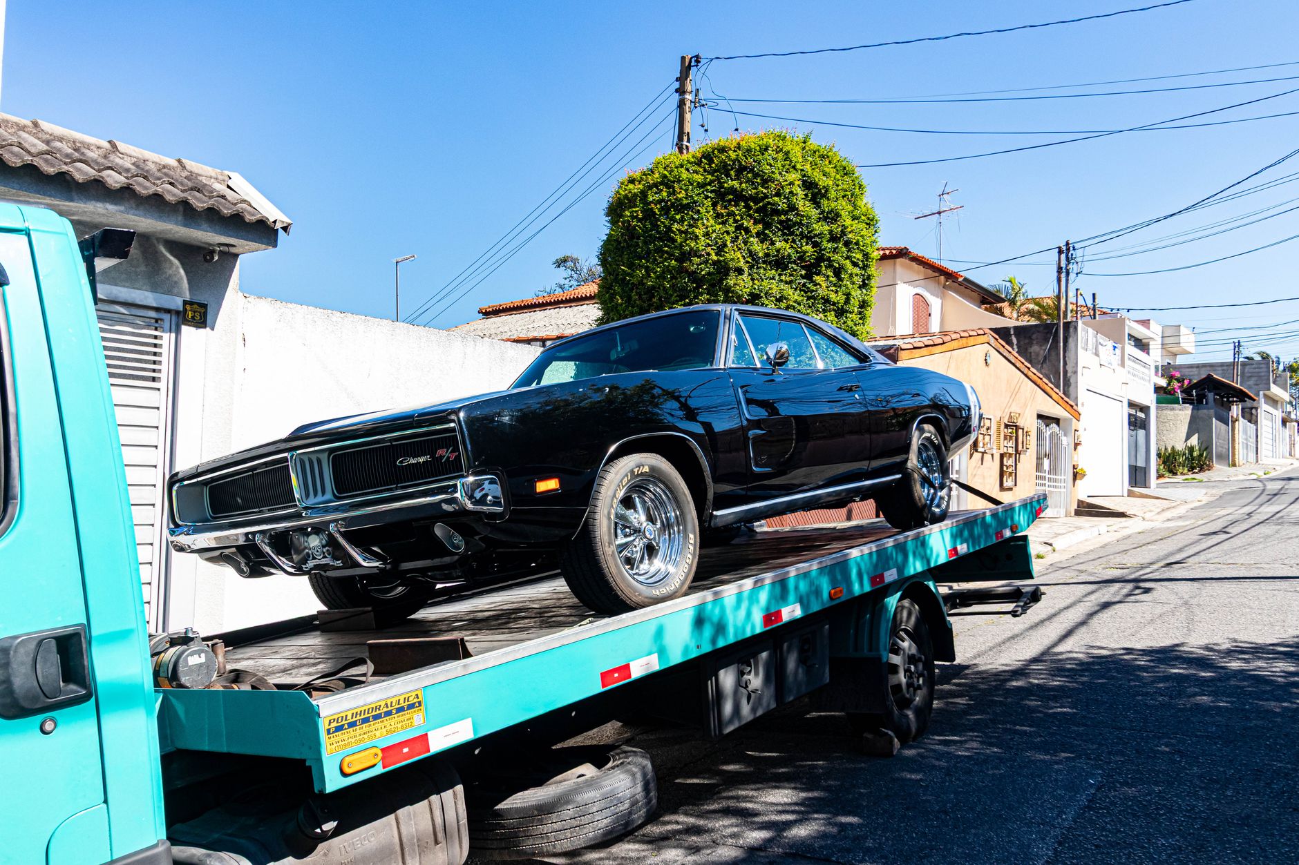 A classic muscle car being transported on a flatbed tow truck