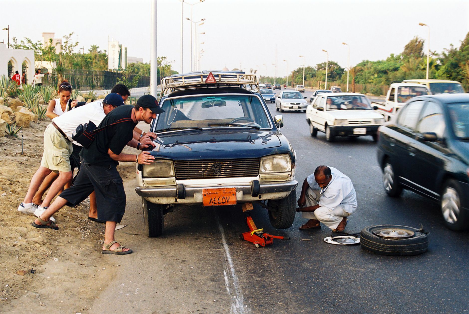 A group helping repair a car on a busy roadside