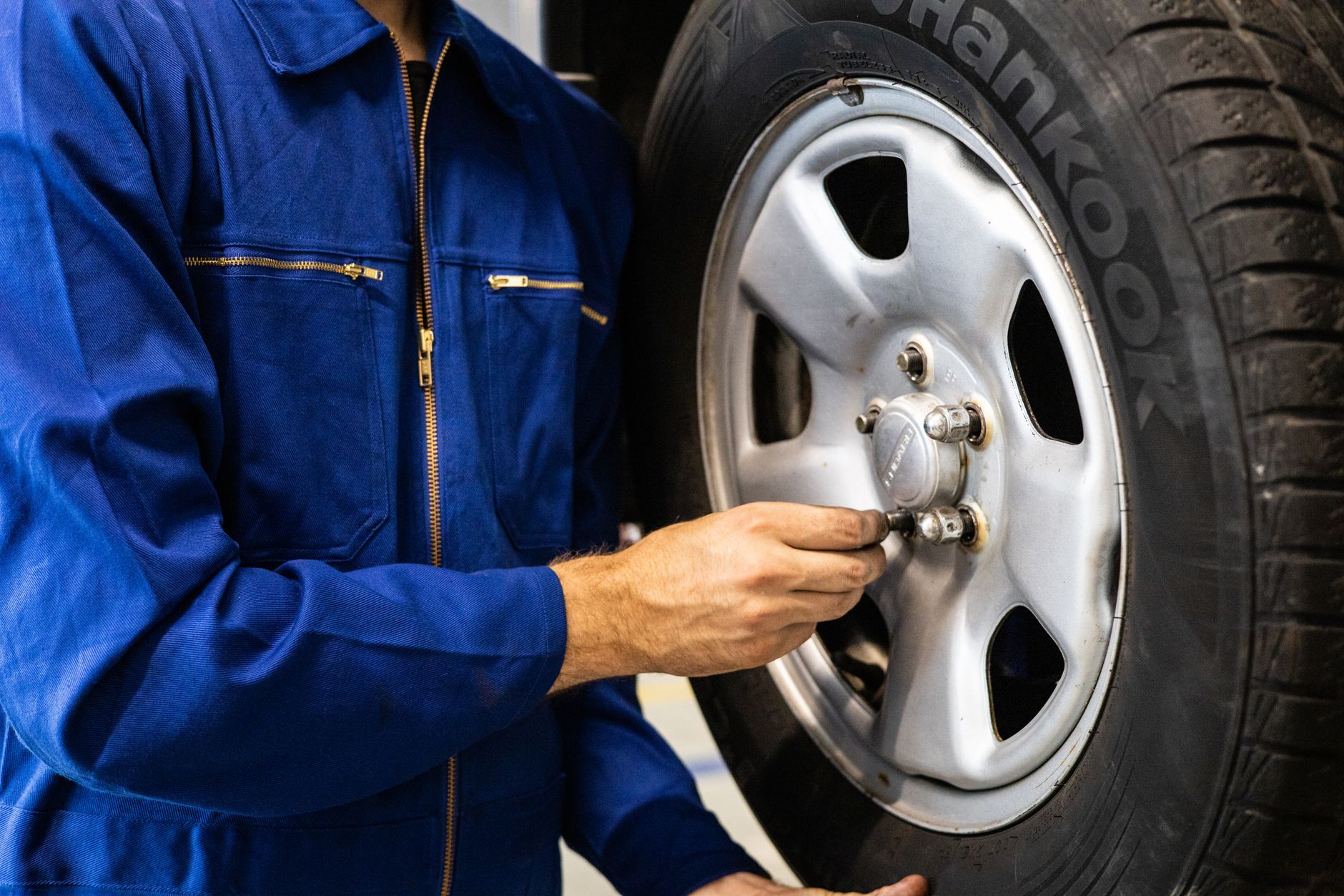 Mechanic in coveralls inspecting a tire in an auto repair workshop