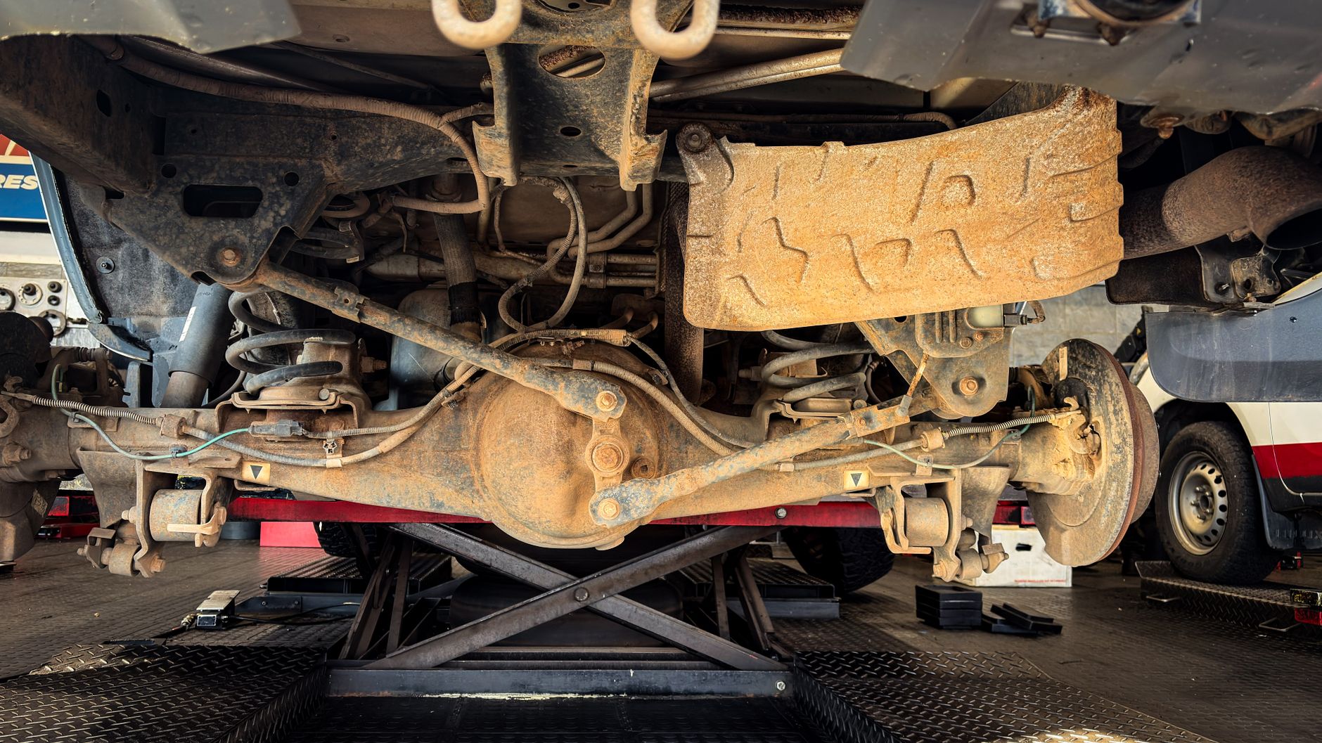 Car suspension and wheel assembly lifted for alignment and repair in a garage